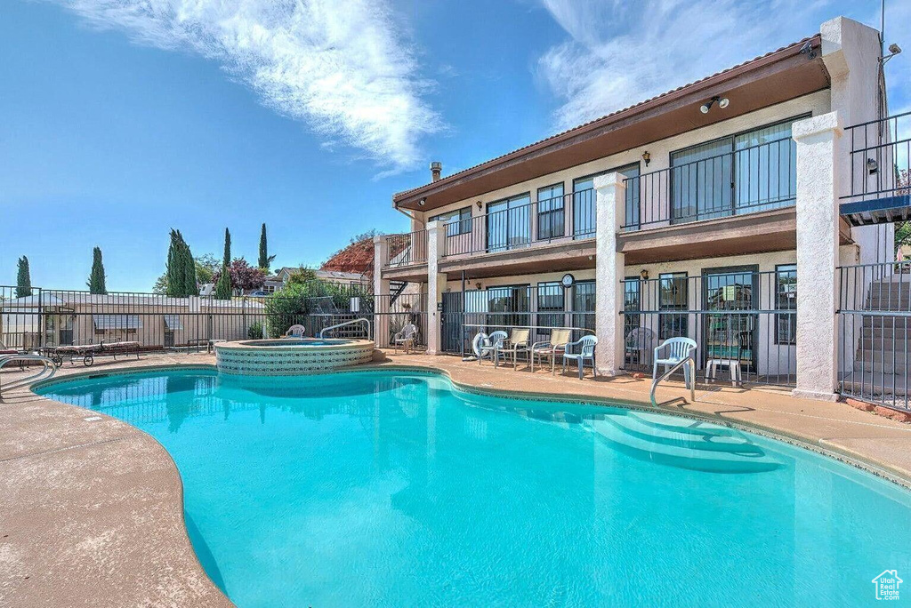 Pool featuring fence, a patio, and a hot tub