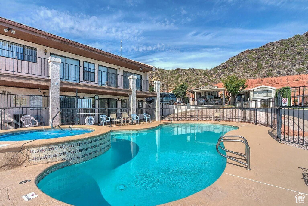 Pool featuring a mountain view, a community hot tub, a patio area, and fence