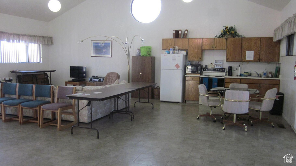Kitchen with light countertops, high vaulted ceiling, freestanding refrigerator, and range with electric stovetop