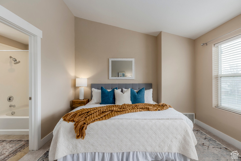Bedroom featuring ensuite bath, visible vents, and baseboards