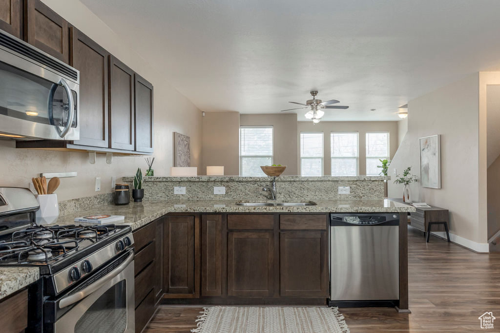 Kitchen with ceiling fan, dark brown cabinetry, a peninsula, appliances with stainless steel finishes, and a sink