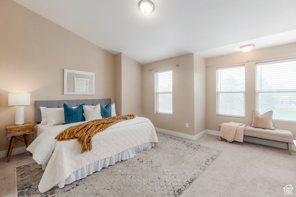 Bedroom featuring light colored carpet, baseboards, and vaulted ceiling