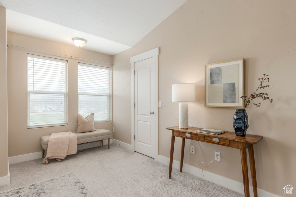 Living area featuring baseboards, vaulted ceiling, and carpet floors