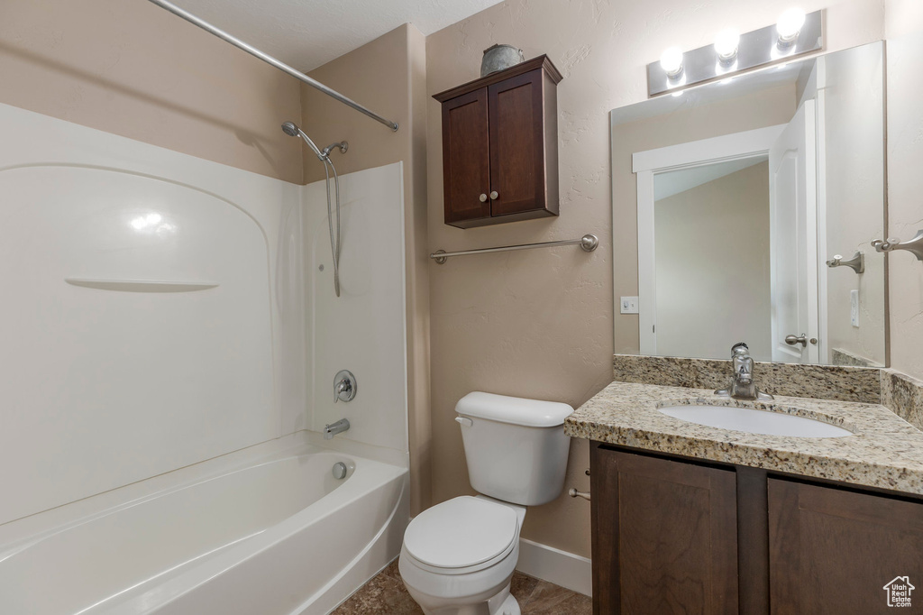 Bathroom with toilet, vanity, shower / washtub combination, and baseboards