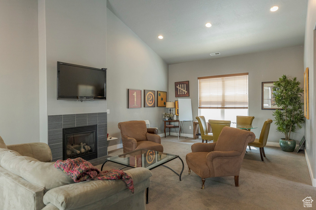 Carpeted living area with baseboards, recessed lighting, a fireplace, visible vents, and high vaulted ceiling