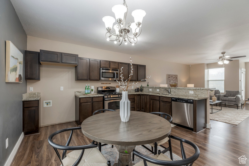 Dining space featuring ceiling fan with notable chandelier, dark wood-style flooring, and baseboards