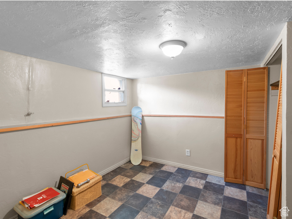 Basement with baseboards and a textured ceiling