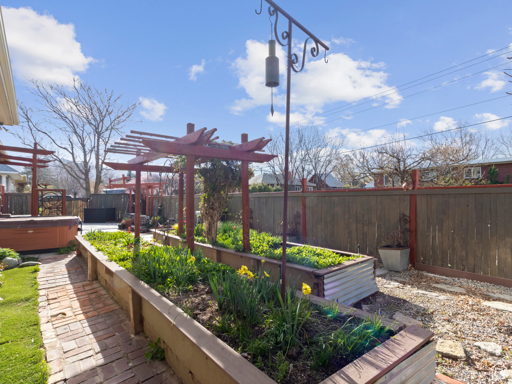 View of yard with a garden, a pergola, fence private yard, and a hot tub