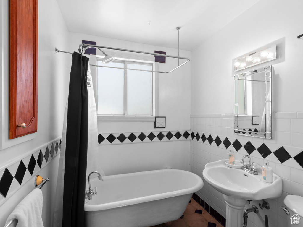 Full bath with a freestanding bath, wainscoting, and tile walls
