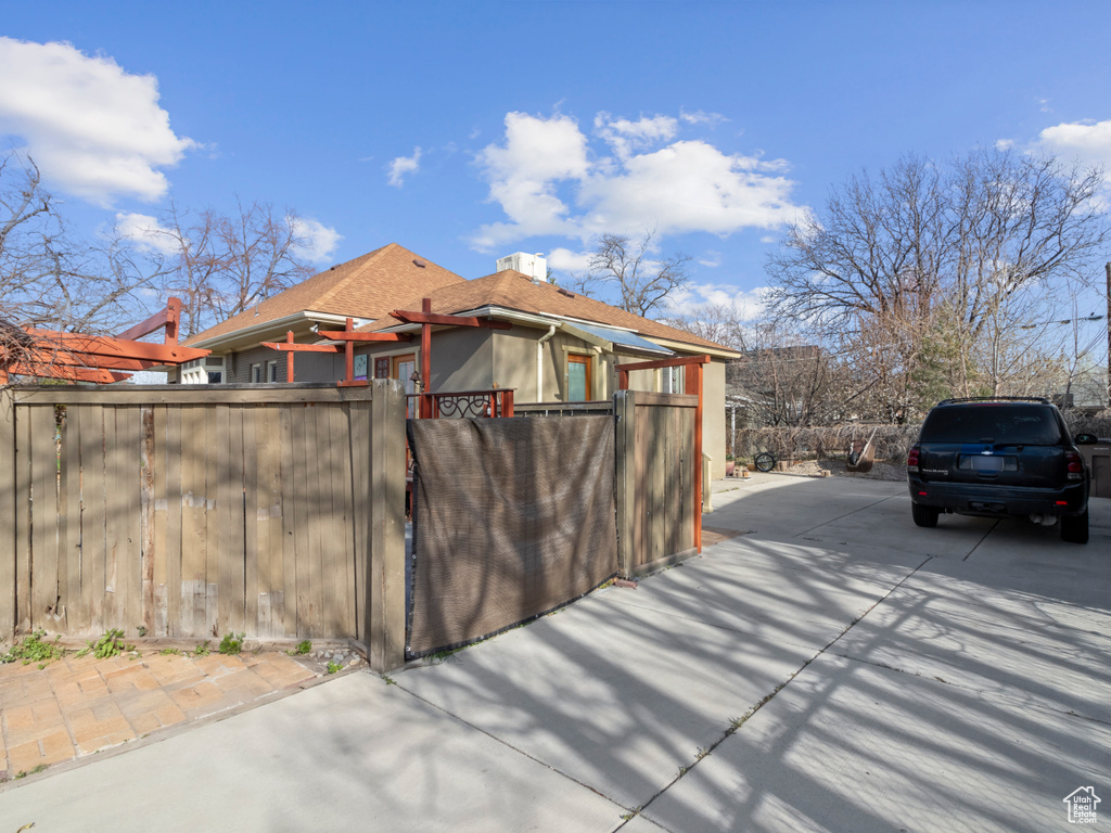 View of side of home with a chimney, fence, and roof with shingles