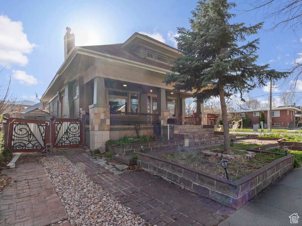 View of front of home with a chimney, covered porch, and a gate