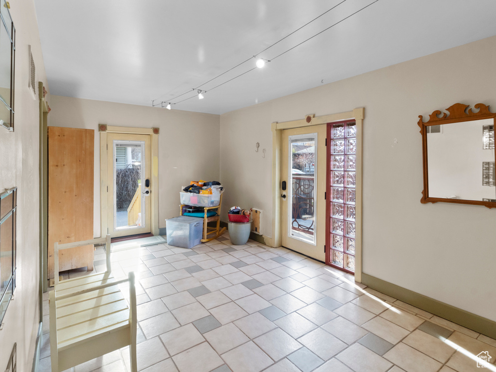 Empty room featuring rail lighting, light tile patterned floors, and baseboards