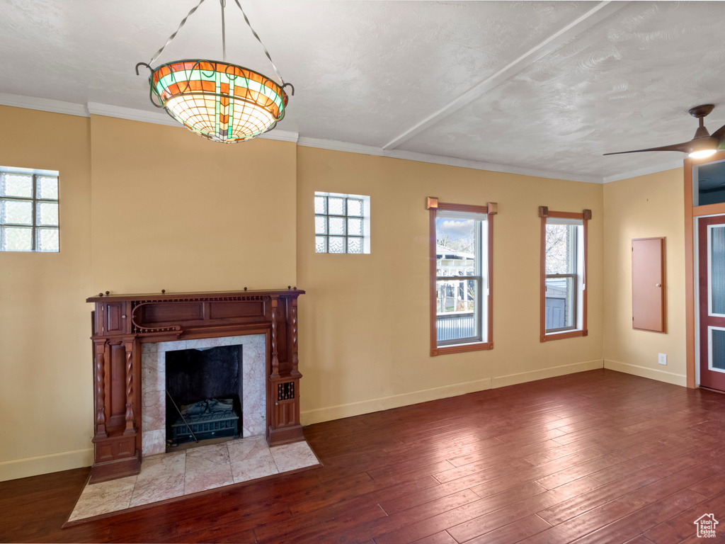 Unfurnished living room featuring baseboards, ceiling fan, crown molding, wood-type flooring, and a premium fireplace