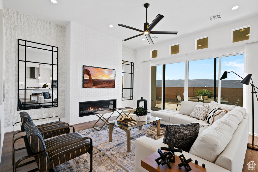 Living area with wood finished floors, a glass covered fireplace, ceiling fan, recessed lighting, and baseboards