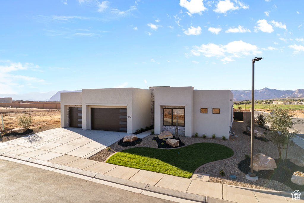 Adobe home featuring a mountain view, stucco siding, an attached garage, and concrete driveway