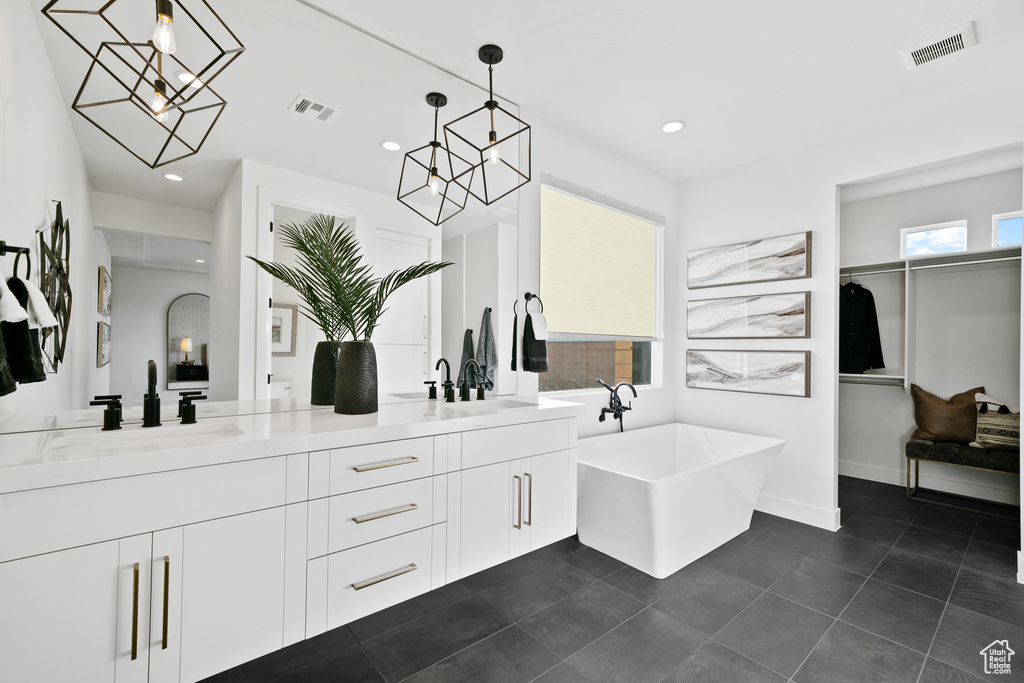 Bathroom featuring double vanity, a soaking tub, recessed lighting, tile patterned floors, and a chandelier