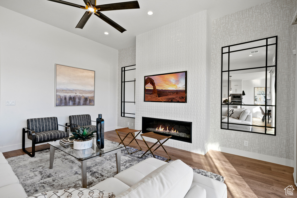 Living area with wood finished floors, baseboards, a large fireplace, a ceiling fan, and recessed lighting