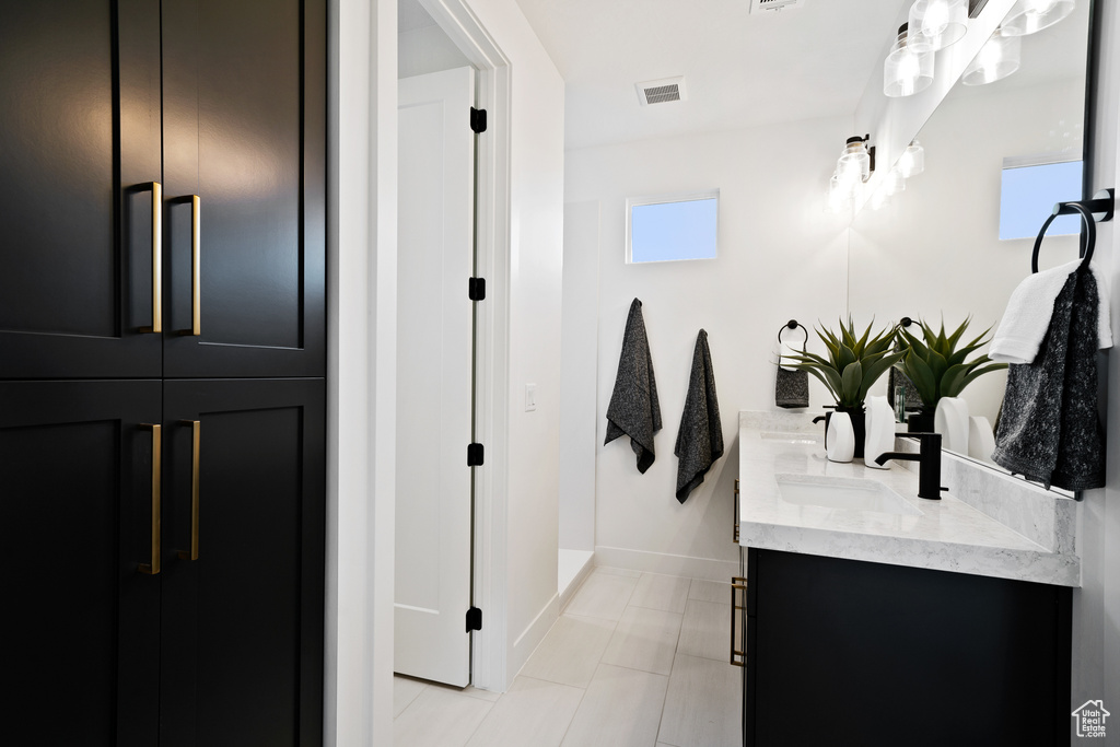 Full bath with double vanity, baseboards, and tile patterned flooring