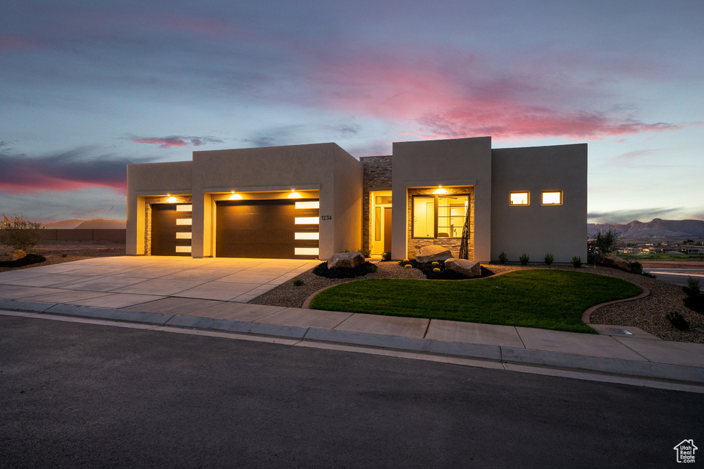 Southwest-style home with a garage, stucco siding, concrete driveway, and a lawn