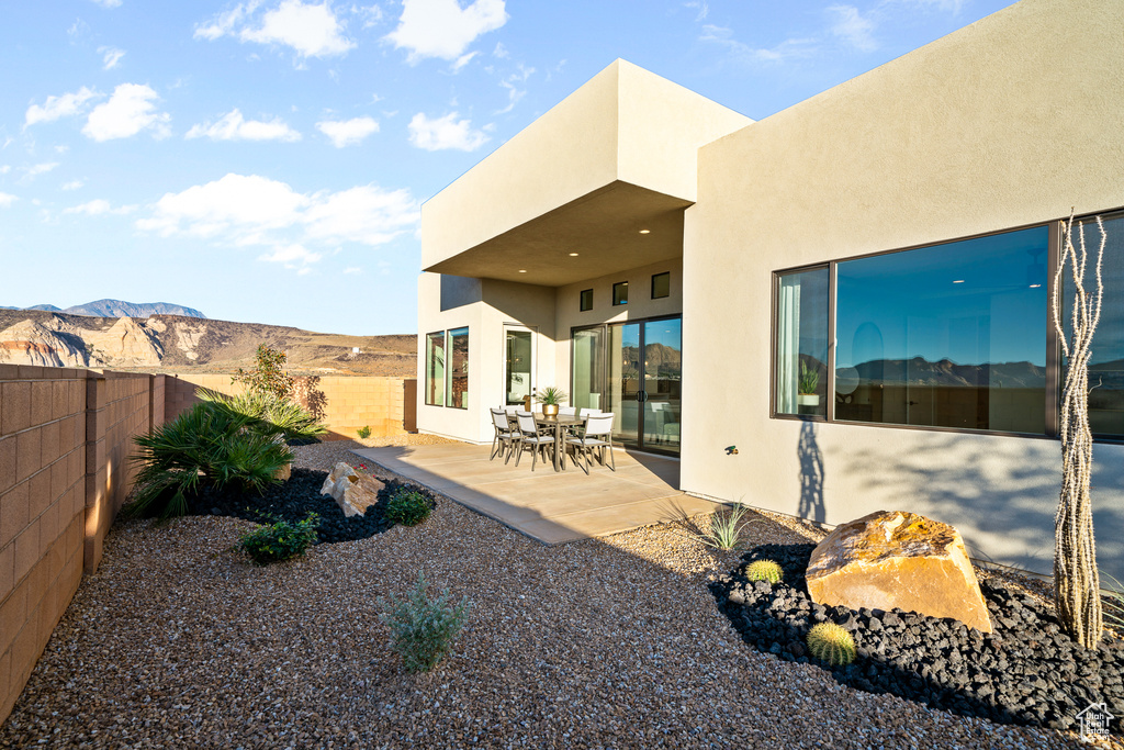 Rear view of property with stucco siding, a patio area, and a mountain view