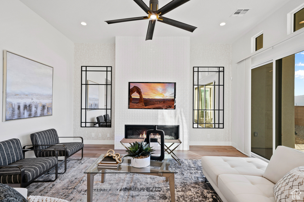 Living room featuring baseboards, a glass covered fireplace, wood finished floors, recessed lighting, and a ceiling fan