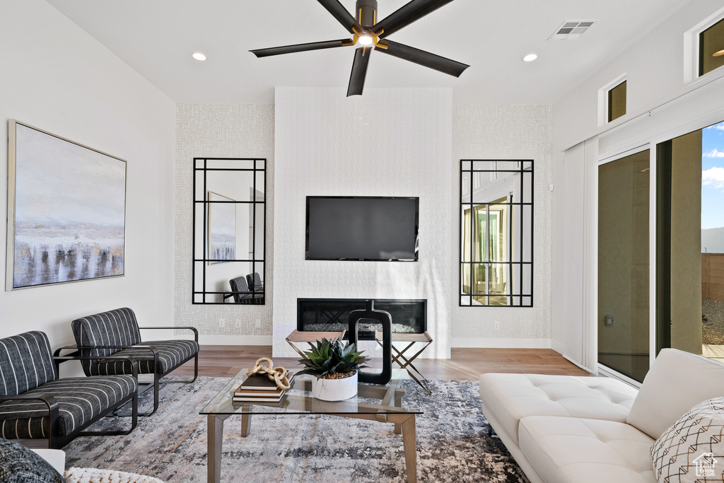Living room featuring baseboards, wood finished floors, a fireplace, recessed lighting, and ceiling fan