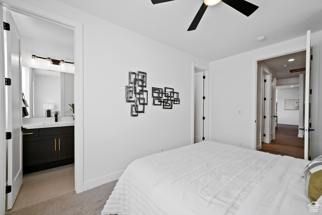 Bedroom with ensuite bath, baseboards, and ceiling fan