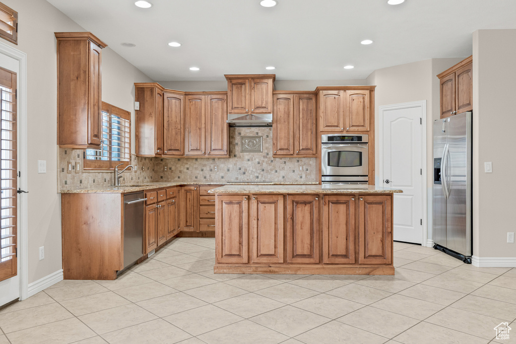 Kitchen with appliances with stainless steel finishes, a sink, backsplash, a center island, and recessed lighting