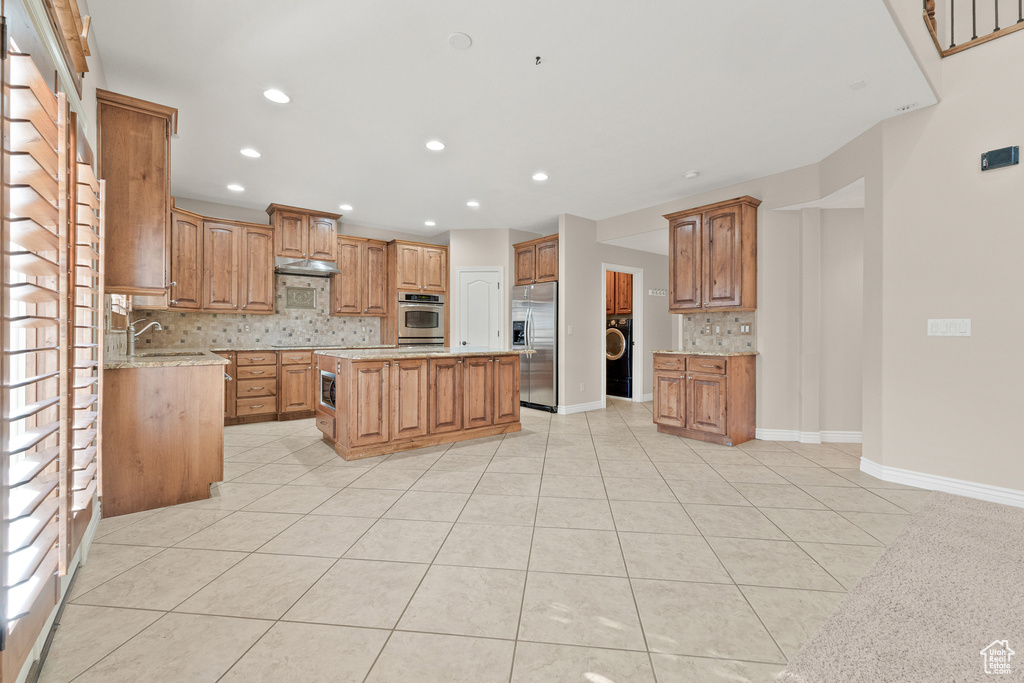 Kitchen featuring stainless steel appliances, backsplash, light tile patterned flooring, a center island, and recessed lighting