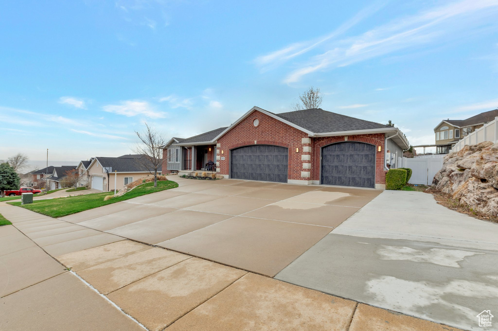 View of front of property with a garage, brick siding, a residential view, driveway, and roof with shingles