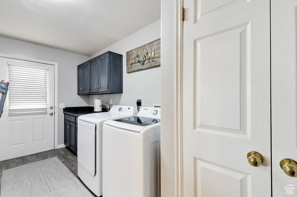 Washroom featuring cabinet space, dark wood-style floors, washer and dryer, and a textured ceiling