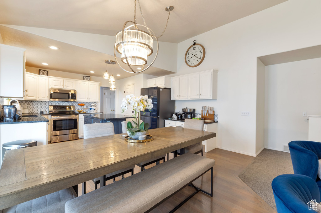 Dining room with baseboards, an inviting chandelier, dark wood-style flooring, recessed lighting, and lofted ceiling