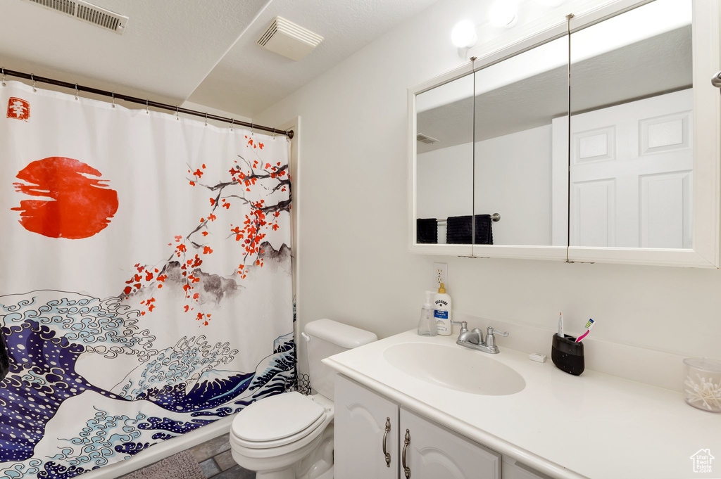 Bathroom with visible vents, toilet, curtained shower, and vanity