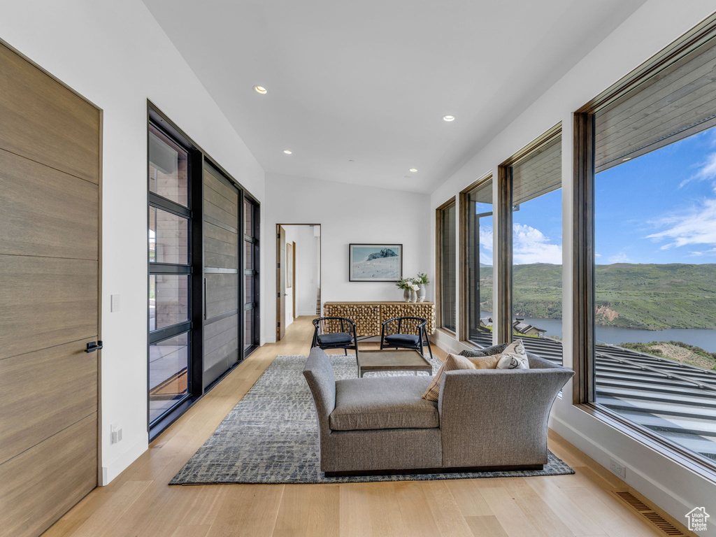 Living room with light wood finished floors, recessed lighting, and a water view