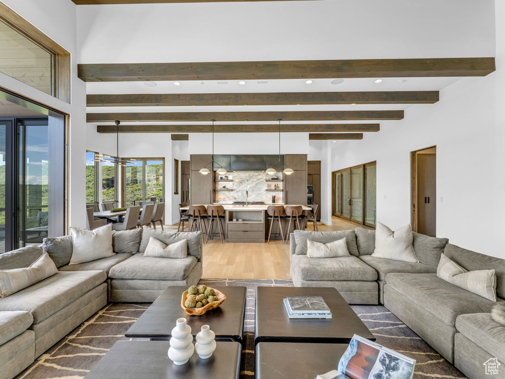 Living area with light wood-style floors, beamed ceiling, and recessed lighting