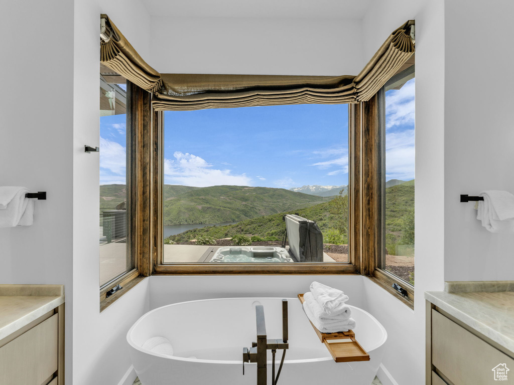 Bathroom with vanity, a freestanding bath, a mountain view, and baseboards