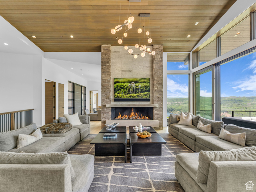 Living area with wood ceiling, a chandelier, a stone fireplace, recessed lighting, and wood finished floors