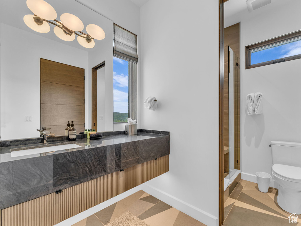 Full bathroom with toilet, vanity, a stall shower, and baseboards