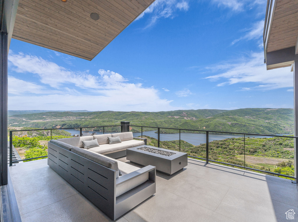 View of patio / terrace featuring a water and mountain view and an outdoor living space with a fire pit