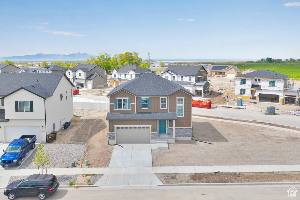 View of front of property featuring a residential view, stone siding, a garage, and concrete driveway