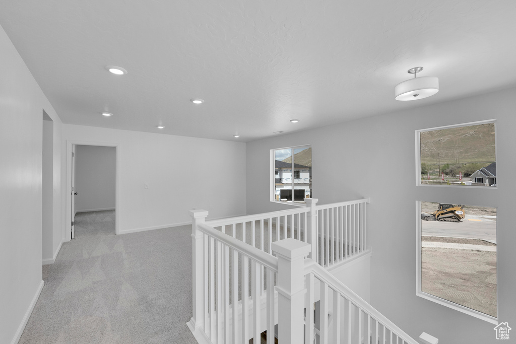 Hall with an upstairs landing, recessed lighting, carpet flooring, and baseboards