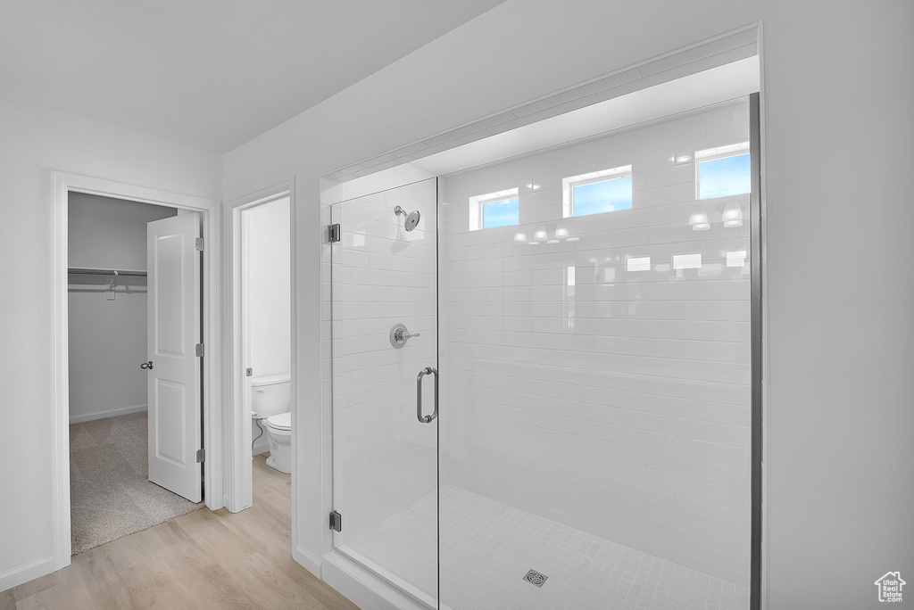 Full bathroom with toilet, a shower stall, wood finished floors, and a spacious closet