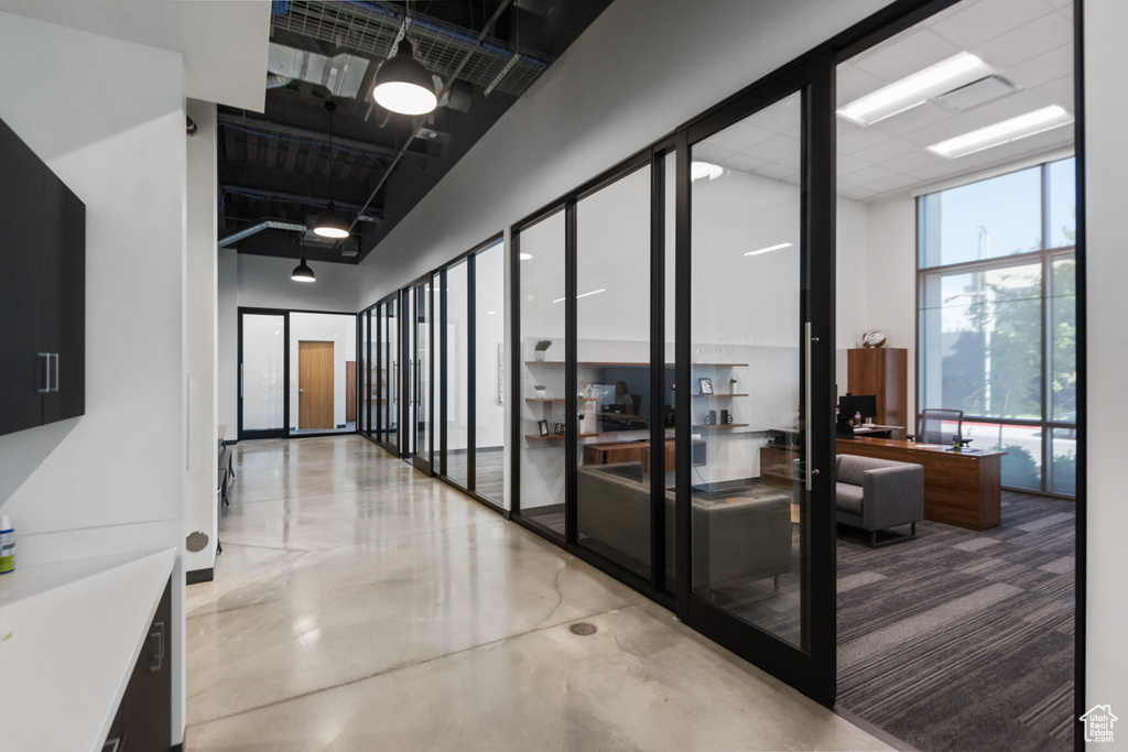Corridor featuring expansive windows, finished concrete flooring, and a high ceiling