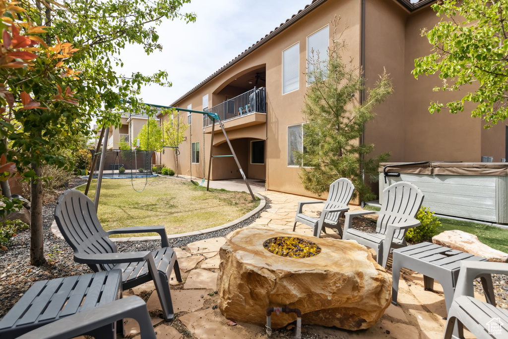 Exterior space featuring a hot tub, a trampoline, a fire pit, and a balcony