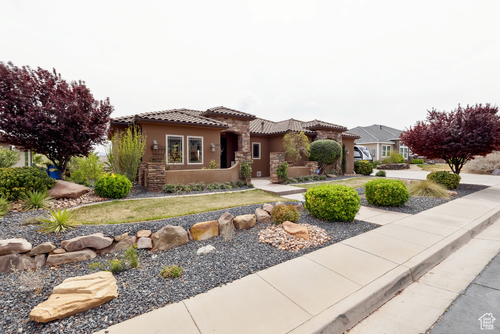 Mediterranean / spanish home featuring a tiled roof, stone siding, and stucco siding