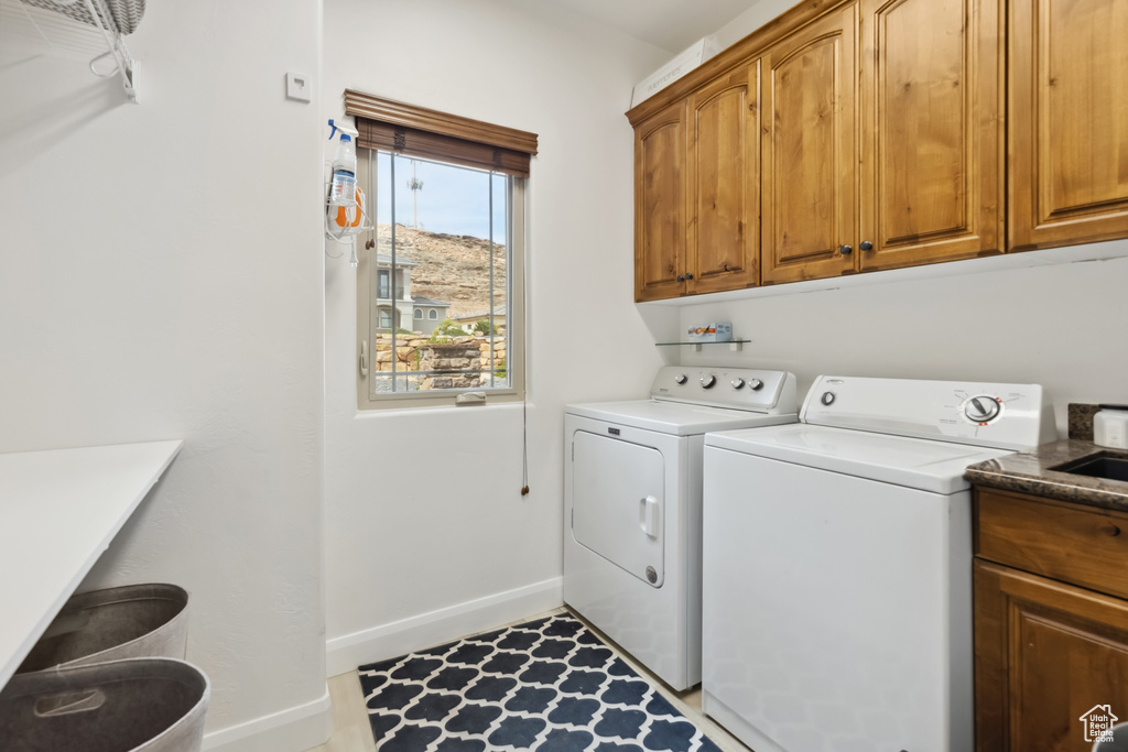 Washroom with separate washer and dryer, baseboards, a sink, and cabinet space