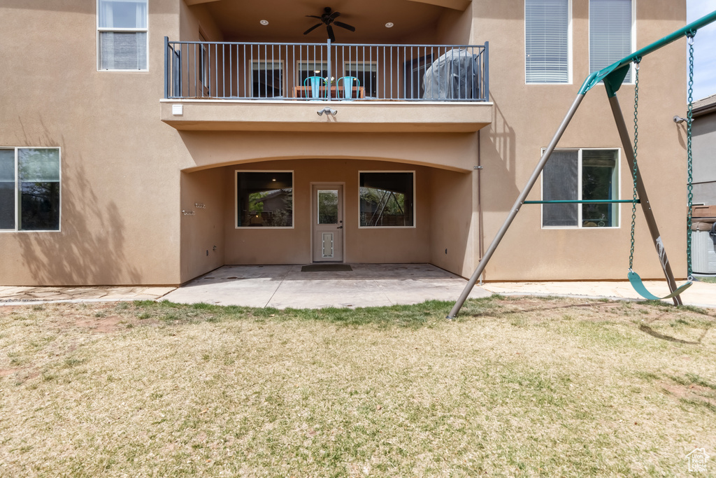 Rear view of house featuring ceiling fan, stucco siding, a patio area, and a lawn