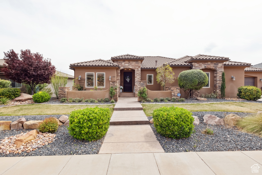 Mediterranean / spanish-style house featuring stucco siding, stone siding, and a tile roof