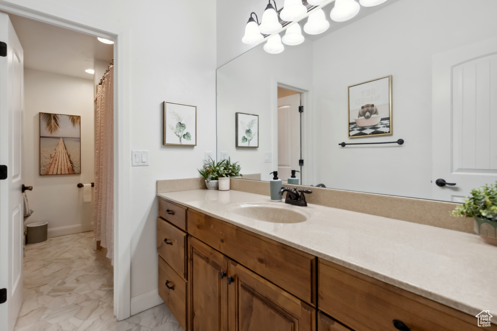 Bathroom featuring a chandelier, baseboards, marble finish floor, and vanity