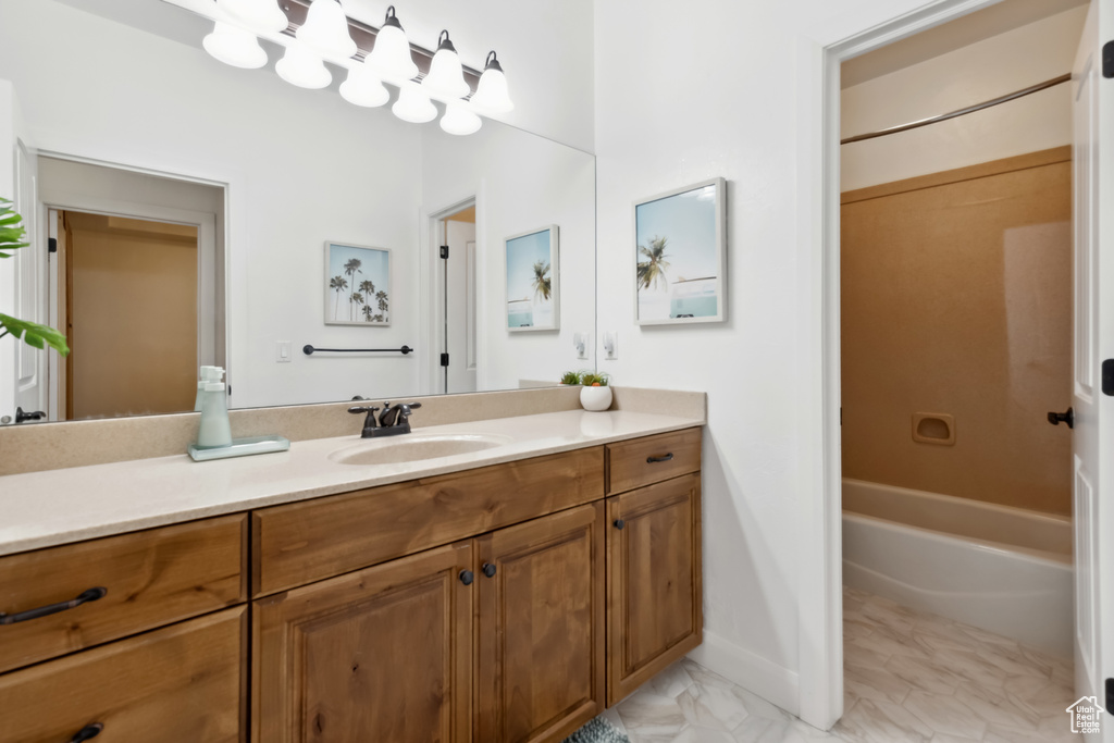 Full bath featuring marble finish floor, vanity, baseboards, and shower / bathtub combination